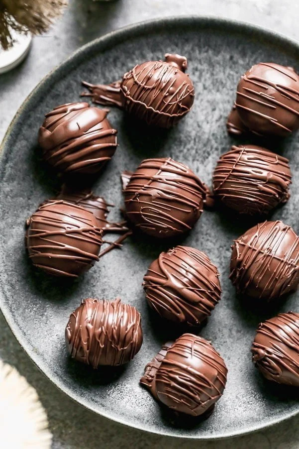 Rice Krispie Peanut Butter Balls are the ultimate no-bake holiday treat! Inside these decadent treats you'll find a mixture of chunky peanut butter, crushed rice cereal, melted butter, and sweet powdered sugar. We roll the filling into balls, dunk it in milk chocolate (or dark if you want!), and inhale them faster than an elf chugs maple syrup.&nbsp;