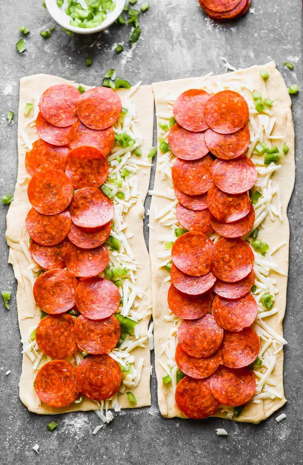 Layer pepperoni, cheese, and peppers on dough. 