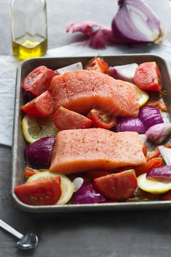 Salmon filets on top of tomatoes, red onion and lemon 
