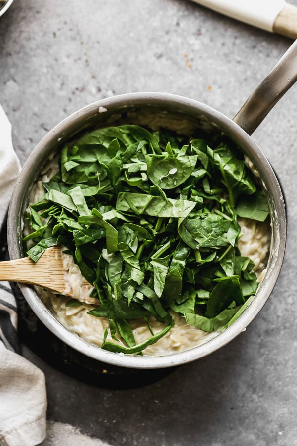 Add spinach to creamy orzo. 