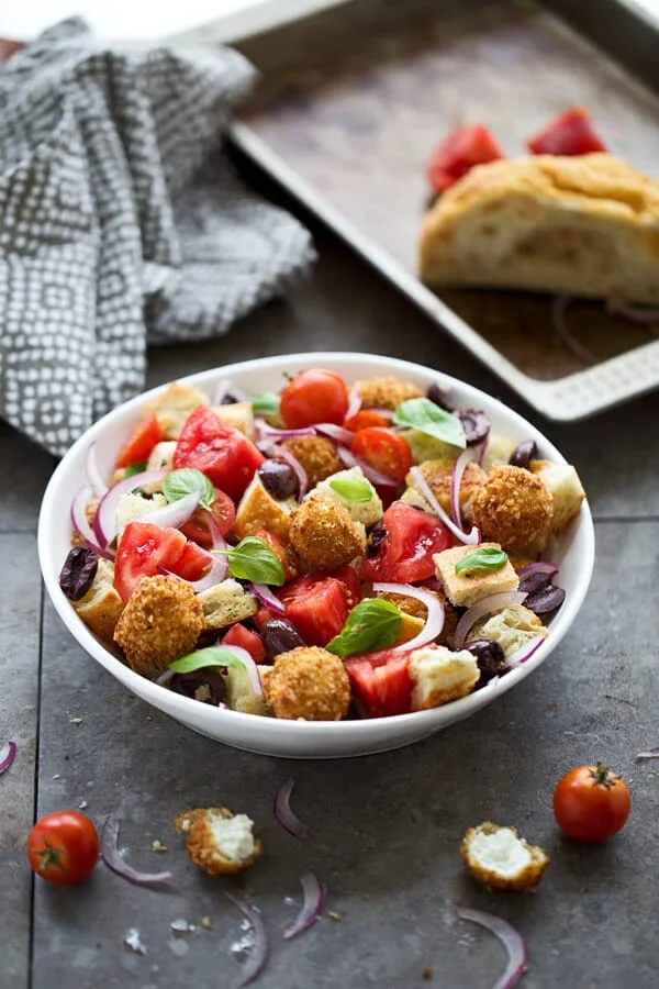 Panzanella salad with fried goat cheese in a round white bowl