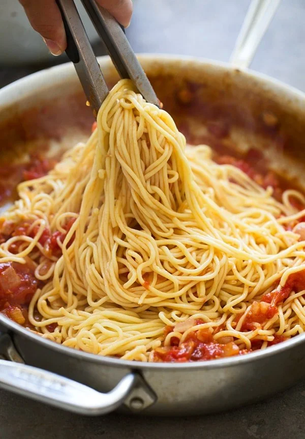 Toss spaghetti in all'amatriciana sauce to finish cooking the pasta