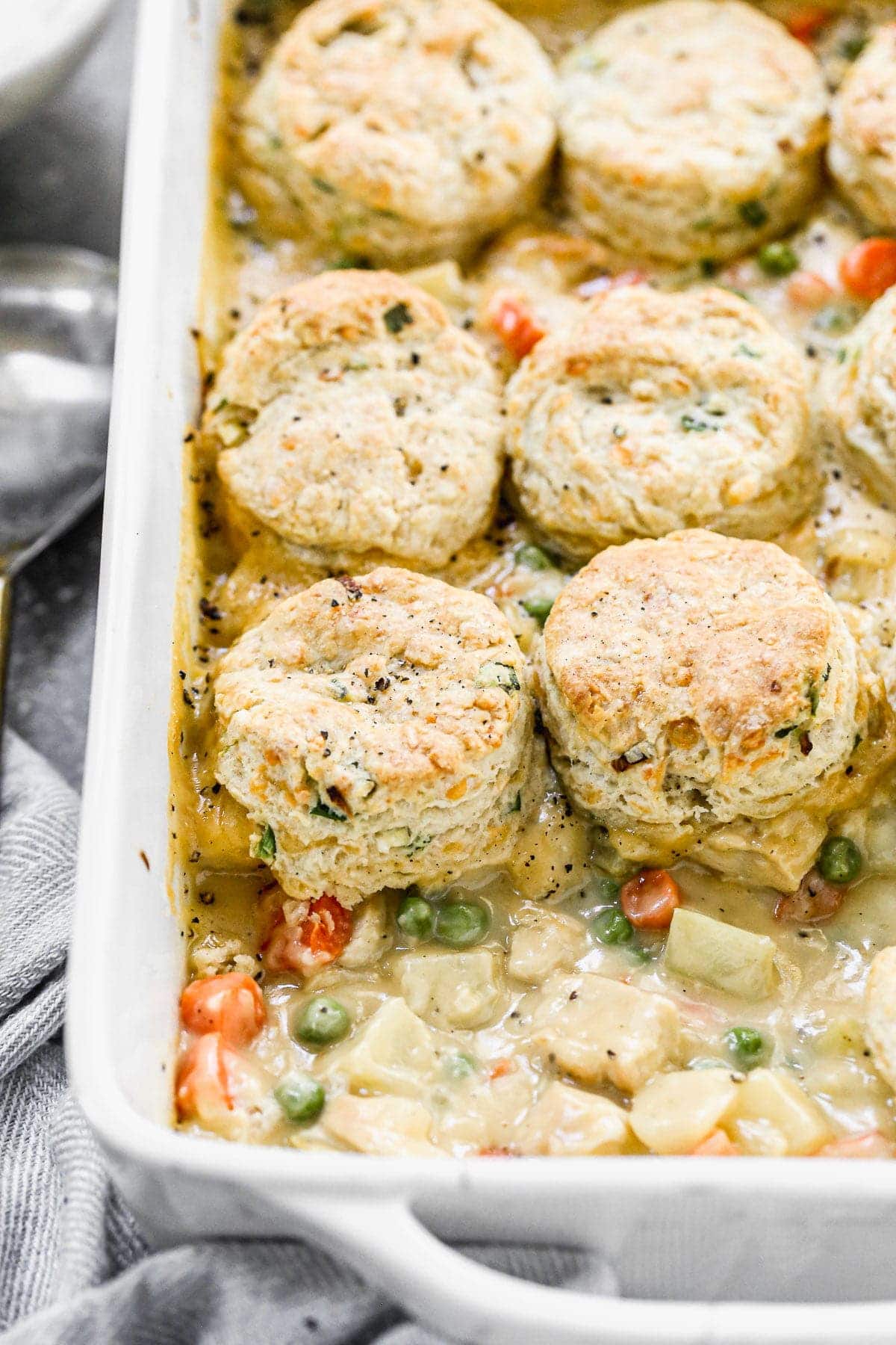 Possibly our favorite comfort food of fall, this Chicken Pot Pie with Biscuits is cozy, delicious and a such fun twist on traditional chicken pot pie. We take a classic creamy pot pie filling full of chicken, carrots, celery, and potatoes and stud it with sharp cheddar cheese and then top it off with fluffy, tender cheddar chive biscuits. Heaven in a casserole dish.