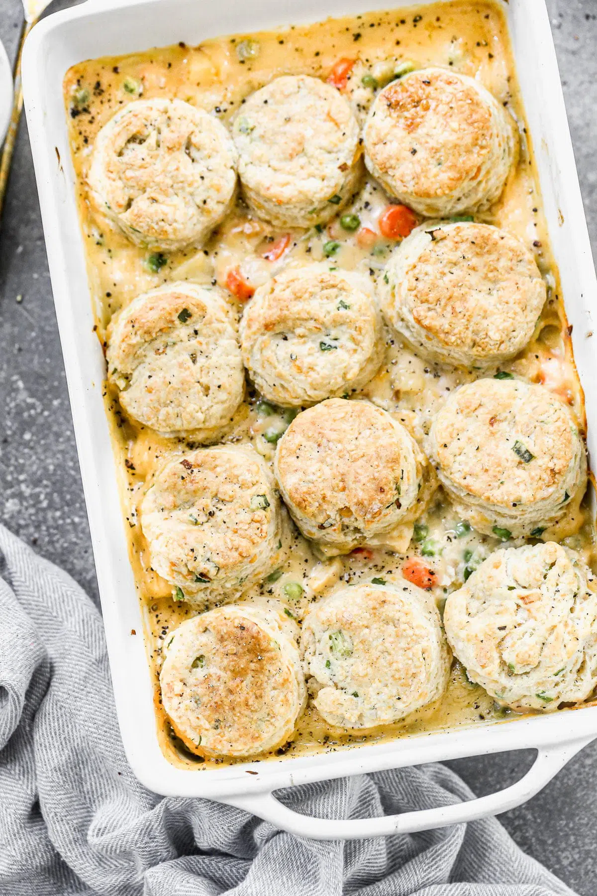 Possibly our favorite comfort food of fall, this Chicken Pot Pie with Biscuits is cozy, delicious and a such fun twist on traditional chicken pot pie. We take a classic creamy pot pie filling full of chicken, carrots, celery, and potatoes and stud it with sharp cheddar cheese and then top it off with fluffy, tender cheddar chive biscuits. Heaven in a casserole dish.