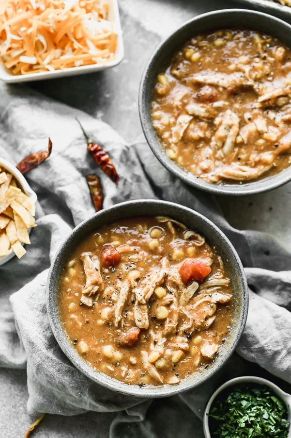 Creamy Chicken Tortilla Soup is spicy, cheesy, creamy, and so delicious! It's packed with dried chiles, canned green chiles and uses corn tortillas instead of cream or cheese for a super creamy texture without adding a ton of fat and calories. Top with homemade tortilla chips, shredded cheese and&nbsp;plenty of sour cream.