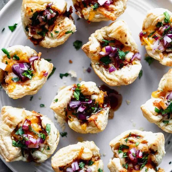 Cheesy Barbecue Chicken Bites: Chopped chicken tossed in your favorite barbecue sauce, covered in cheese and served with chopped red onion and cilantro. The perfect bite-sized appetizer for a crowd!