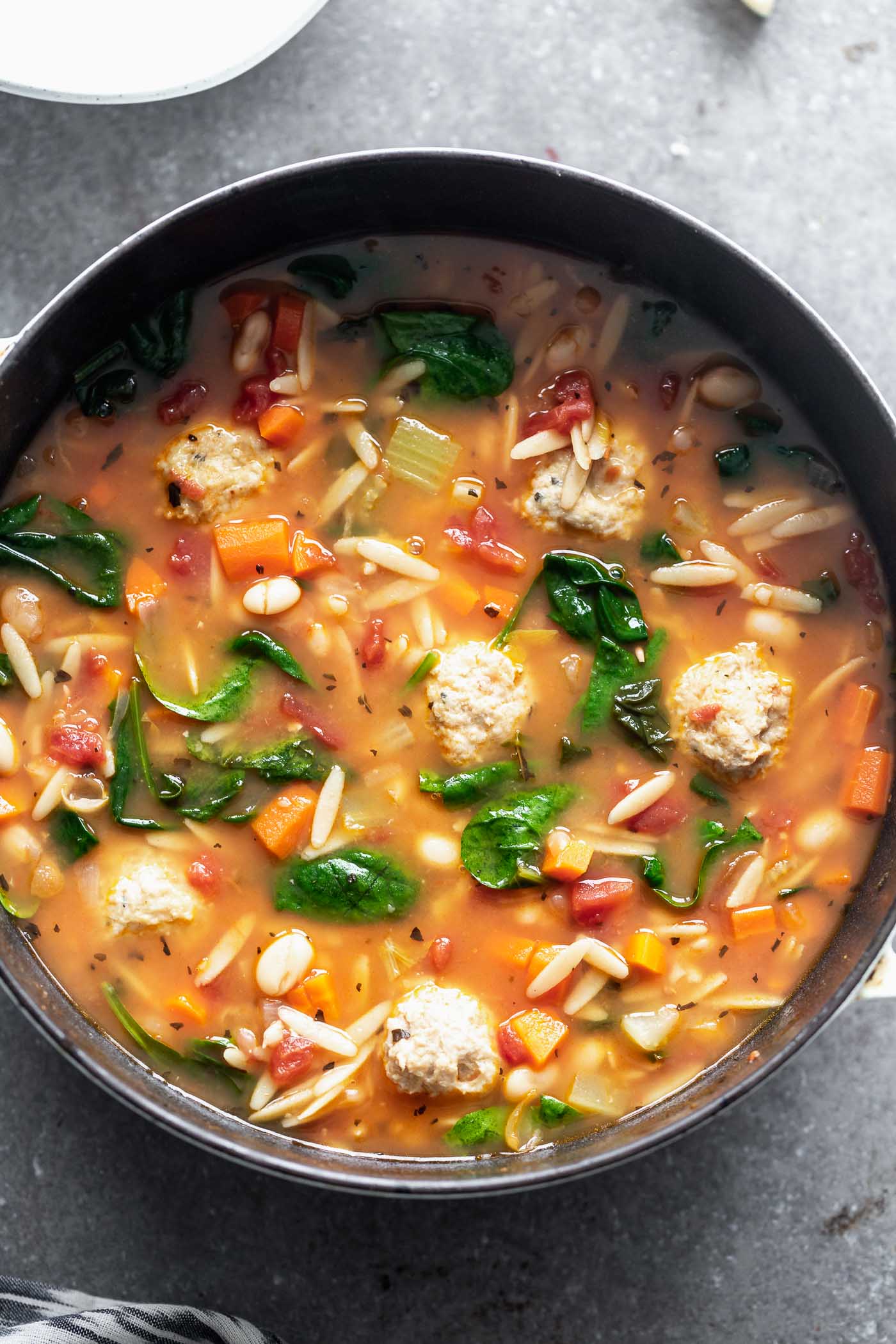 Minestrone with Chicken Meatballs is a hybrid of two comforting soups - minestrone and Italian wedding soup. With a rich, parmesan-infused broth, tons of veggies, whole-wheat orzo, and the most tender, flavorful chicken meatballs, this is a healthy winter soup worth making over and over again.