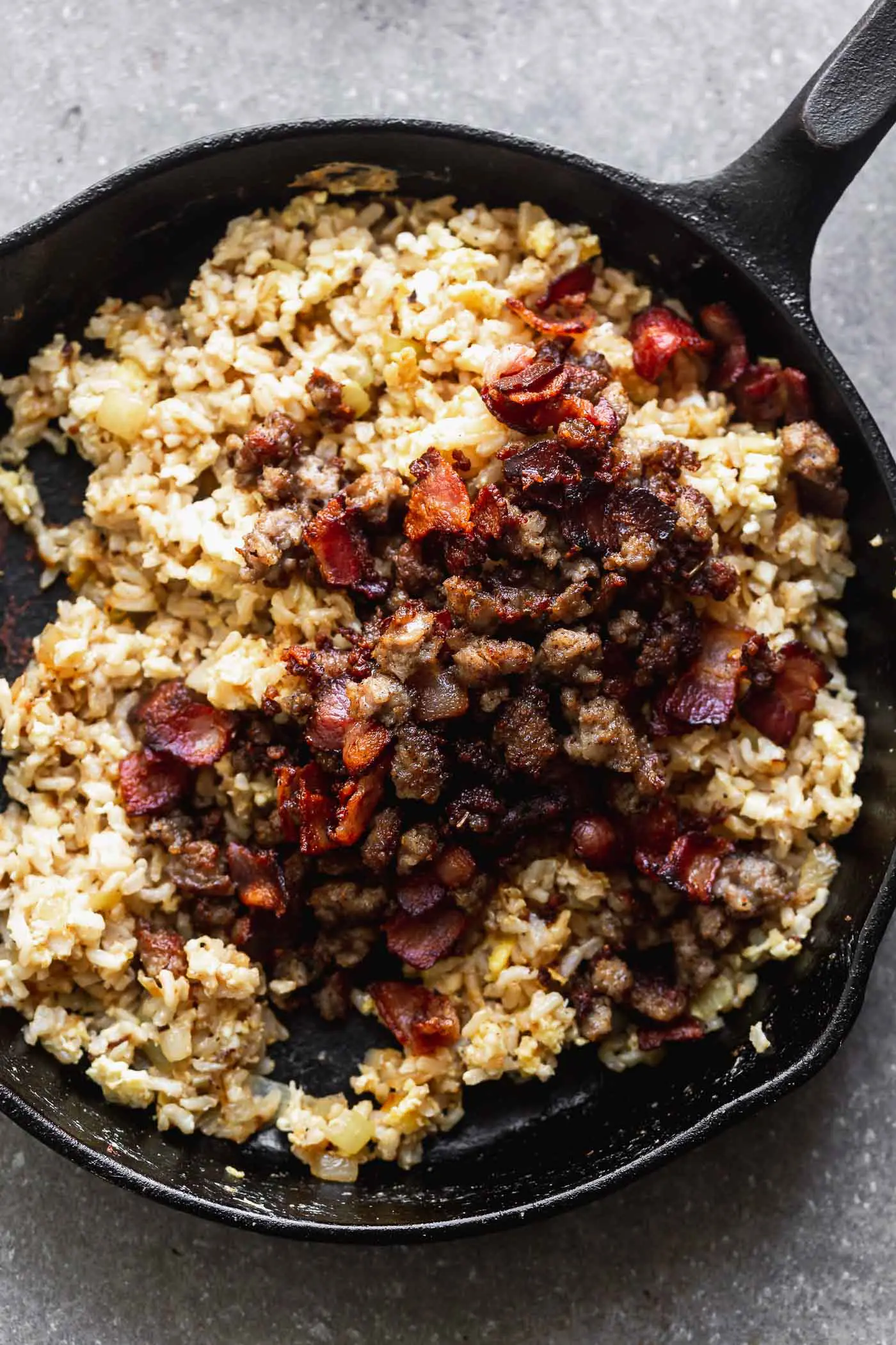 This Breakfast Fried Rice Recipe is packed with salty bacon and sausage, a light soy sauce, oniob, garlic, and plenty of hearty scrambled eggs. 