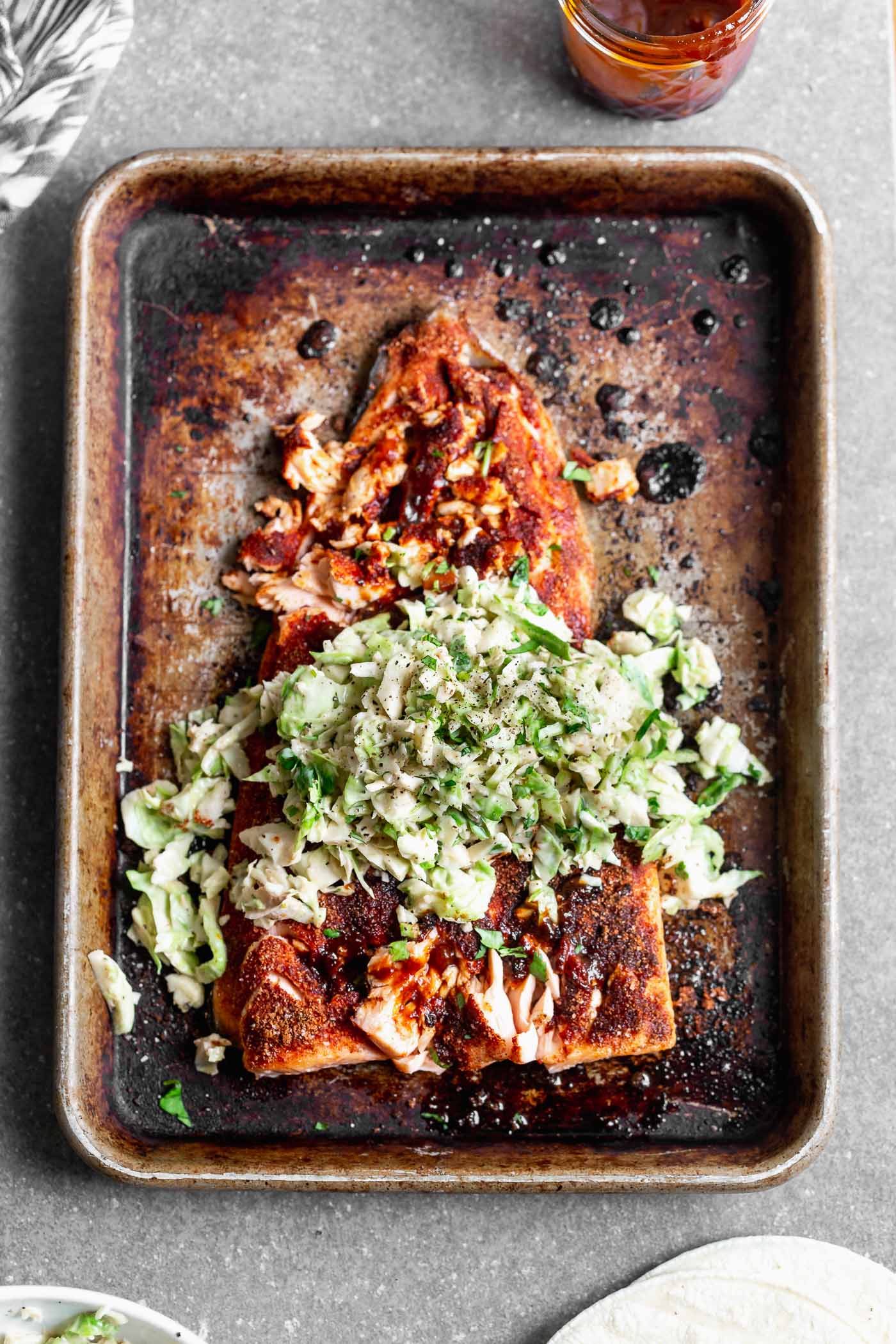 This Baked BBQ Salmon with Brussels Sprout Slaw is one of our favorite ways to serve salmon! We press a sweet and spicy dry rub on the surface of the fish, bake until crispy on the outside and buttery on the inside. We slather the salmon with homemade barbecue sauce and top with a cool, crisp Brussels sprout slaw. Serve as is, or nestle into tortillas for the perfect taco.