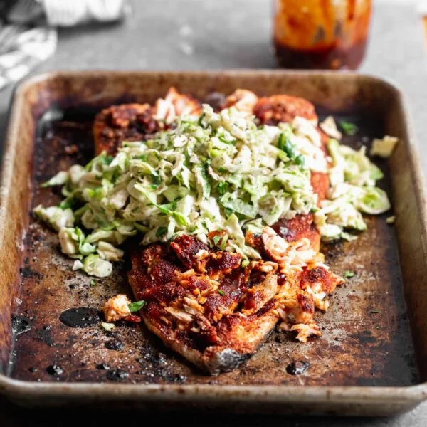 This Baked BBQ Salmon with Brussels Sprout Slaw is one of our favorite ways to serve salmon! We press a sweet and spicy dry rub on the surface of the fish, bake until crispy on the outside and buttery on the inside. We slather the salmon with homemade barbecue sauce and top with a cool, crisp Brussels sprout slaw. Serve as is, or nestle into tortillas for the perfect taco.
