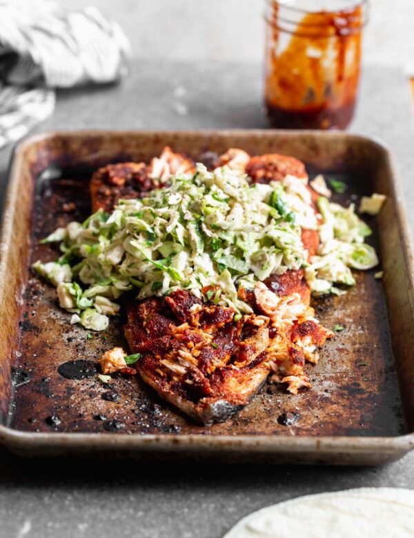 This Baked BBQ Salmon with Brussels Sprout Slaw is one of our favorite ways to serve salmon! We press a sweet and spicy dry rub on the surface of the fish, bake until crispy on the outside and buttery on the inside. We slather the salmon with homemade barbecue sauce and top with a cool, crisp Brussels sprout slaw. Serve as is, or nestle into tortillas for the perfect taco.