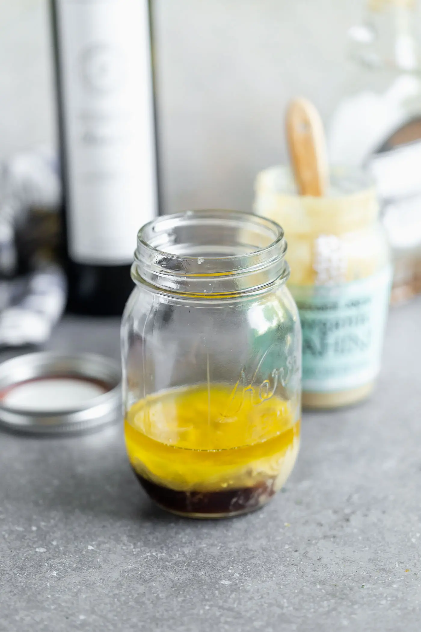 Add tahini, maple syrup, lemon juice, dijon, olive oil, salt, and water to a mason jar.