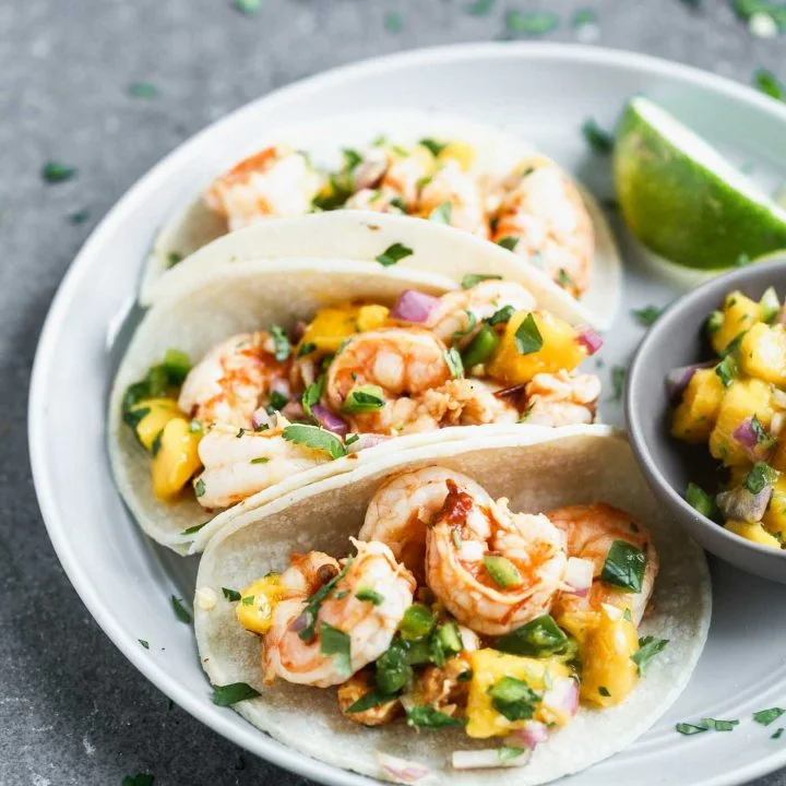 These Easy Chipotle Shrimp Tacos with Mango Salsa are perfect for breezy summer lunches, healthy dinners, or any kind of celebration. Plump shrimp are flavored with chipotle peppers, lime juice, and honey, baked and nestled into corn tortillas (or lettuce wraps!). Each taco is topped off with a quick homemade mango salsa, a little bit of cilantro, and ready to be served!