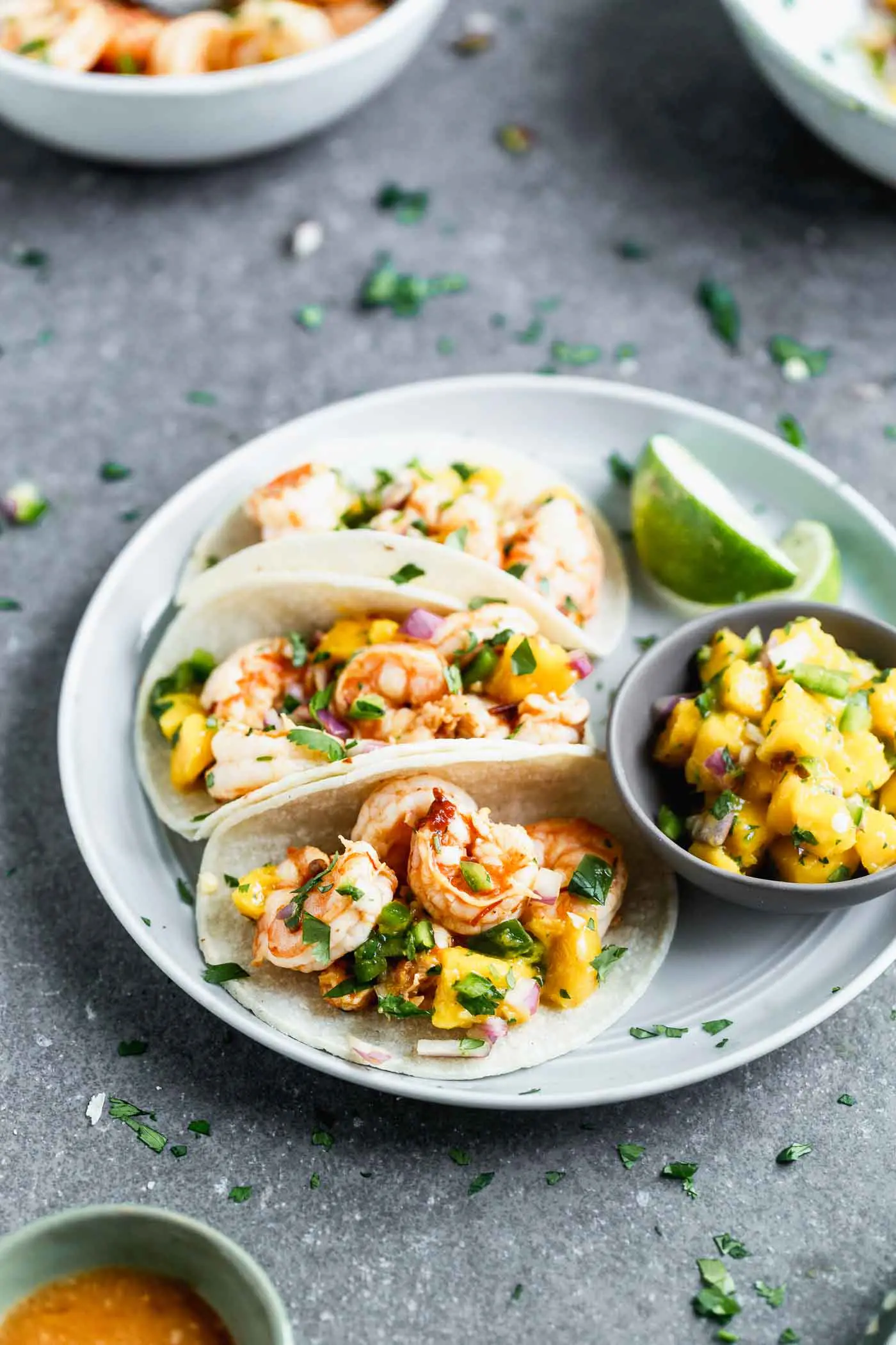 These Easy Chipotle Shrimp Tacos with Mango Salsa are perfect for breezy summer lunches, healthy dinners, or any kind of celebration. Plump shrimp are flavored with chipotle peppers, lime juice, and honey, baked and nestled into corn tortillas (or lettuce wraps!). Each taco is topped off with a quick homemade mango salsa, a little bit of cilantro, and ready to be served!