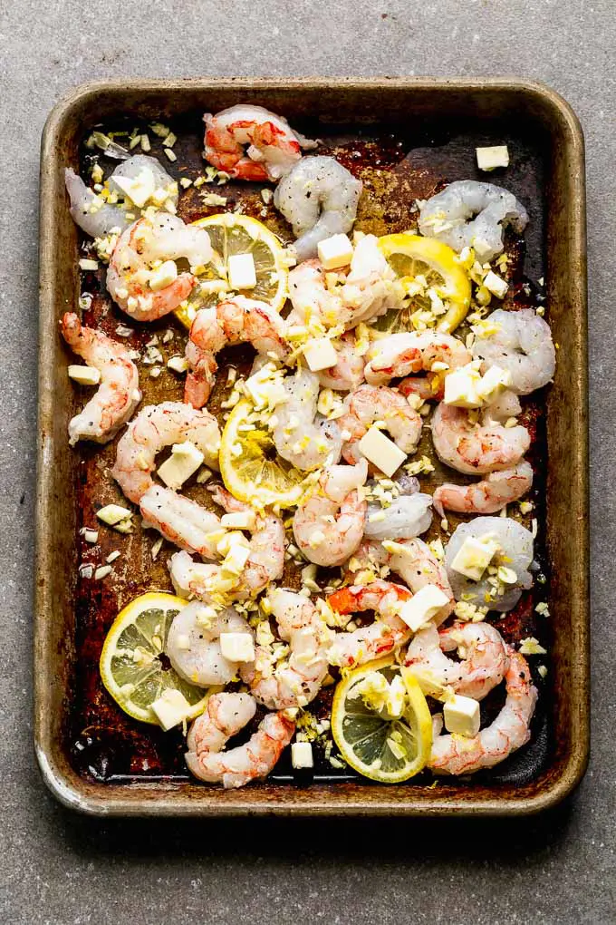 Sprinkle shrimp with chopped garlic, lemon zest, lemon juice, sliced lemons, and just a little bit of butter. 