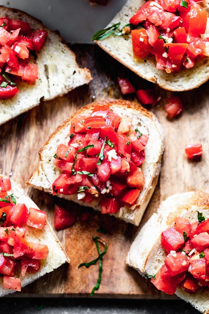 Tomato Basil Bruschetta is a classic Italian appetizer, and something everyone should make when tomatoes are at their peak. This version is completely authentic with just tomatoes, basil, olive oil, and a little bit of salt and pepper to season the tomatoes.  It's served with crusty Italian bread, and that's it!