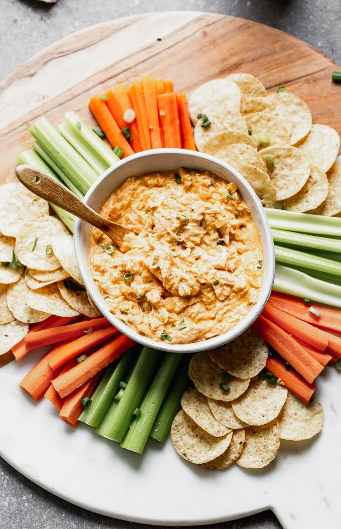 This Healthy Buffalo Chicken Dip (without cream cheese) is the perfect way to get you buffalo Game Day fix without all the fat and calories. Greek yogurt is simmered with sautéed onion and garlic, buffalo sauce, a little bit of blue cheese, a touch of mayo, and plenty of tender shredded chicken. Serve with carrots, celery, and your favorite baked chips. 