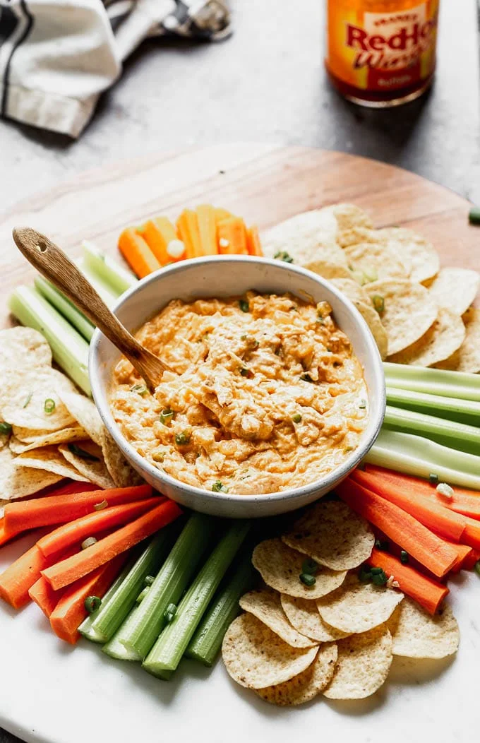 This Healthy Buffalo Chicken Dip (without cream cheese) is the perfect way to get you buffalo Game Day fix without all the fat and calories. Greek yogurt is simmered with sautéed onion and garlic, buffalo sauce, a little bit of blue cheese, a touch of mayo, and plenty of tender shredded chicken. Serve with carrots, celery, and your favorite baked chips.&nbsp;