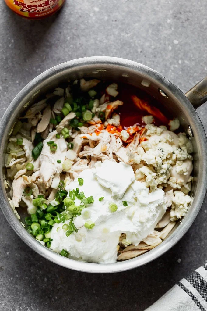 Add buffalo sauce, chicken, green onions, blue cheese, and Greek yogurt to a saucepan.