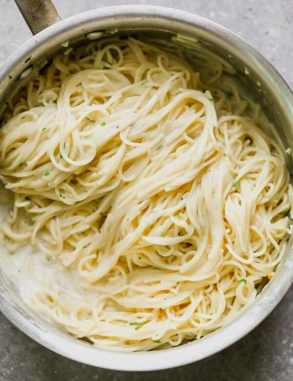 This One Pot Garlic Parmesan Pasta is creamy, slightly cheesy, and so darn good. Angel hair pasta is cooked in a mixture of chicken broth and milk until the pasta is perfectly aldente and swimming in a creamy sauce. It's laced with the perfect amount of parmesan, a tiny bit of butter and plenty of fresh parsley. Perfect to serve as a side or alongside chicken or shrimp for a full meal. 