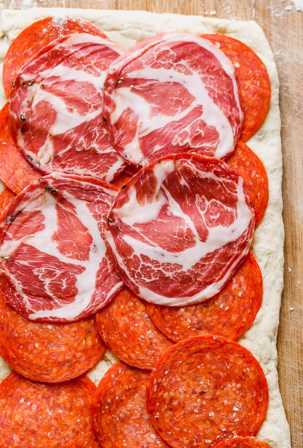 Layer the pepperoni and capicola on the dough