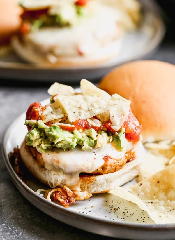 These Spicy Mexican Burgers are packed with all the best classic taco components. Spicy, smoky chicken patties, covered in gooey pepper jack cheese and smothered with smashed avocado, hot salsa, and crunchy tortilla chips.