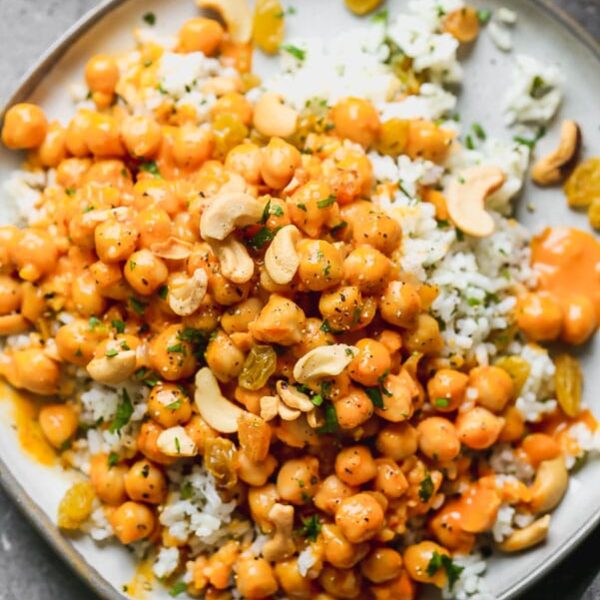 This Chickpea Vegetable Curry is what meat-free dreams are made of. Hearty chickpeas are simmered in a super easy red curry and coconut sauce until they're soft and infused with the rich flavor. The saucy chickpeas are served over a bed of jasmine rice studded with golden raisins, crunchy cashews, and lots of chopped cilantro.