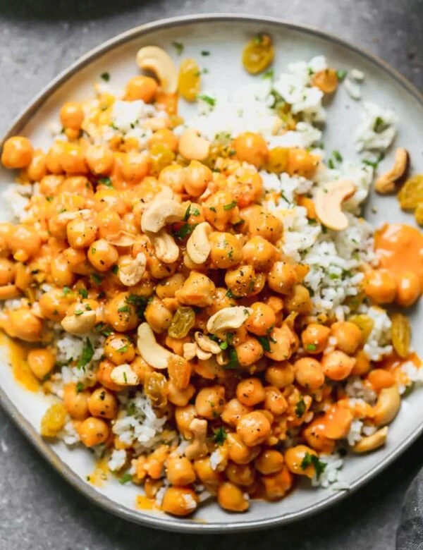 This Chickpea Vegetable Curry is what meat-free dreams are made of. Hearty chickpeas are simmered in a super easy red curry and coconut sauce until they're soft and infused with the rich flavor. The saucy chickpeas are served over a bed of jasmine rice studded with golden raisins, crunchy cashews, and lots of chopped cilantro.