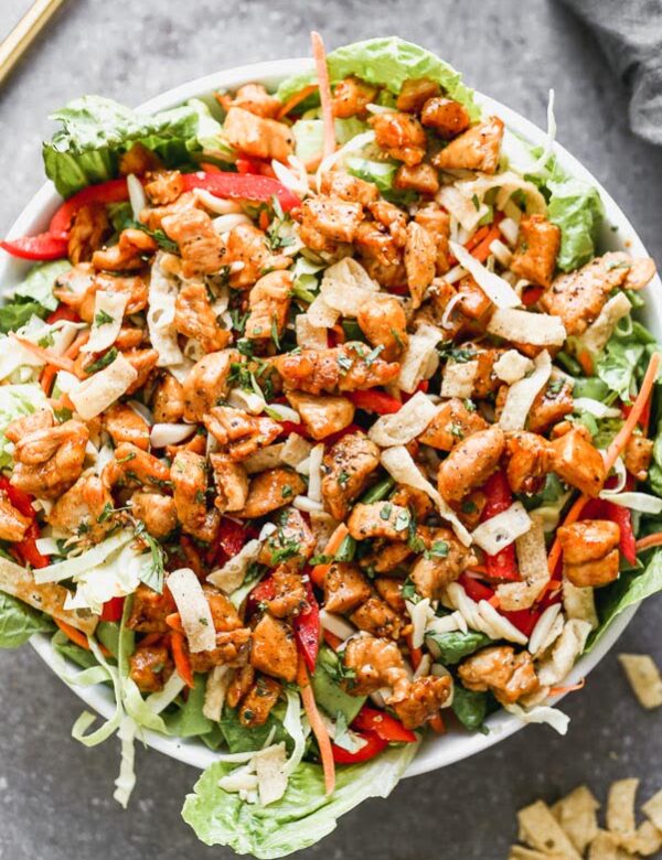 Thai Peanut Chicken Salad is packed with crisp cabbage, plenty of veggies, slivered almonds, and crunchy wonton noodles. It's tossed in a quick sesame vinaigrette and topped off with crispy, saucy peanut-laced chicken. So many delicious flavors and textures happening here!