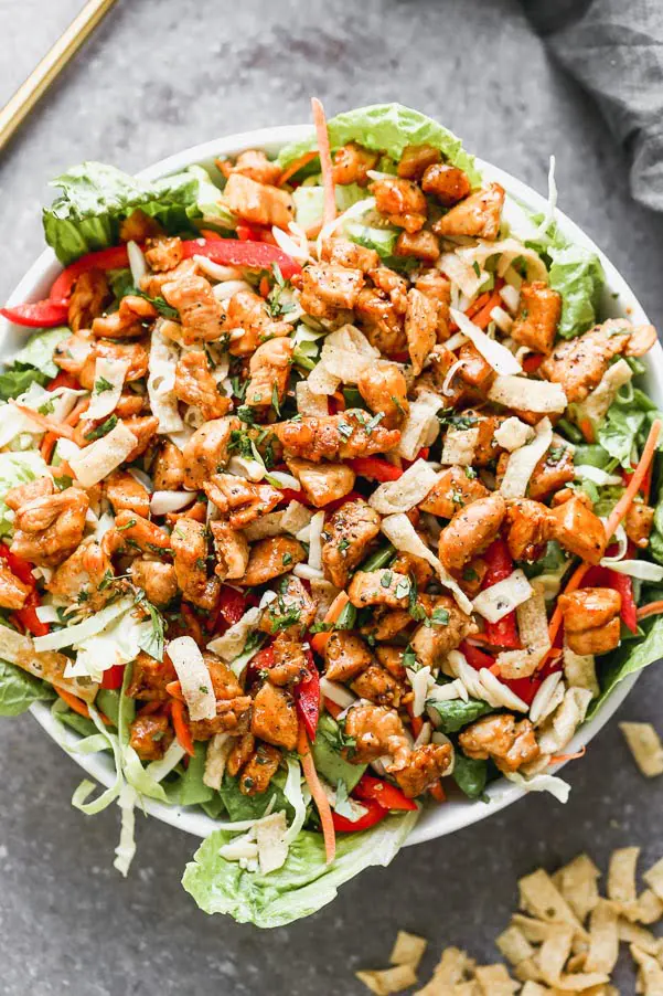 Thai Peanut Chicken Salad is packed with crisp cabbage, plenty of veggies, slivered almonds, and crunchy wonton noodles. It's tossed in a quick sesame vinaigrette and topped off with crispy, saucy peanut-laced chicken. So many delicious flavors and textures happening here!