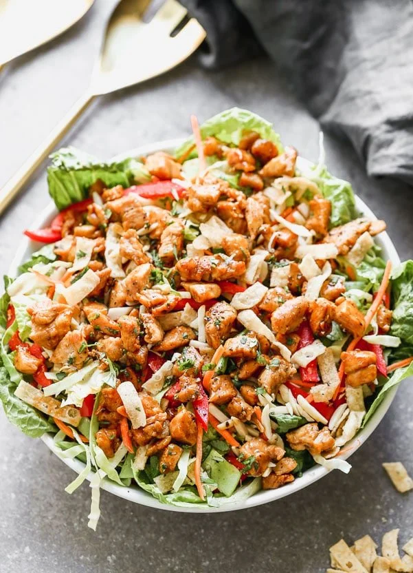 Thai Peanut Chicken Salad is packed with crisp cabbage, plenty of veggies, slivered almonds, and crunchy wonton noodles. It's tossed in a quick sesame vinaigrette and topped off with crispy, saucy peanut-laced chicken. So many delicious flavors and textures happening here!