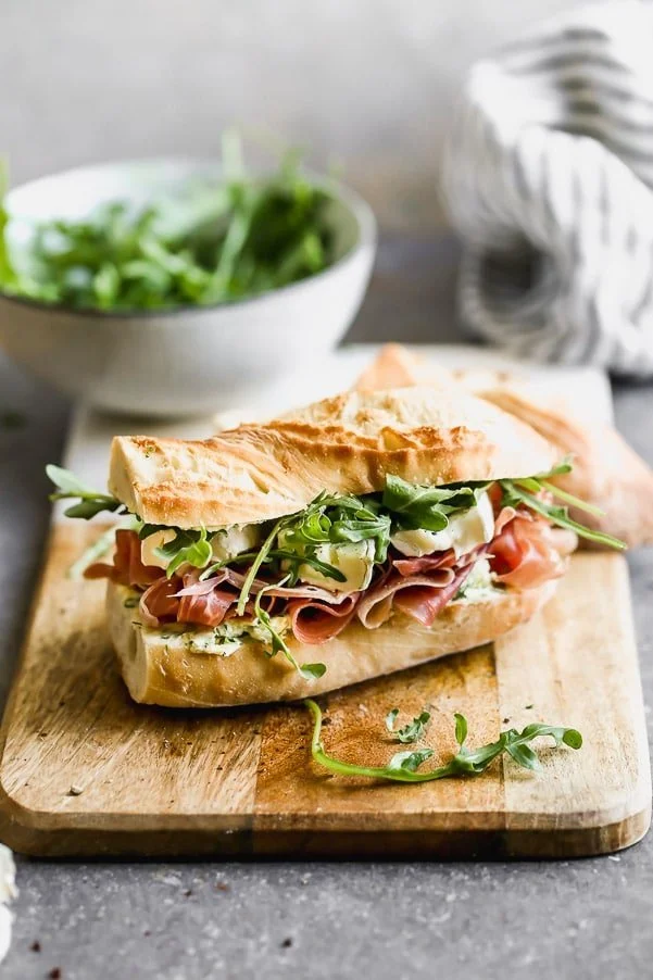 This classic French Baguette Sandwich, also known as a Jambon Beurre Sandwich is such a nice departure from a classic deli sandwich. Our version is layered on a crusty French baguette with salty prosciutto, an easy herbed butter, creamy brie, and peppery arugula. Effortlessly elegant, and most importantly, so delicious.&nbsp;