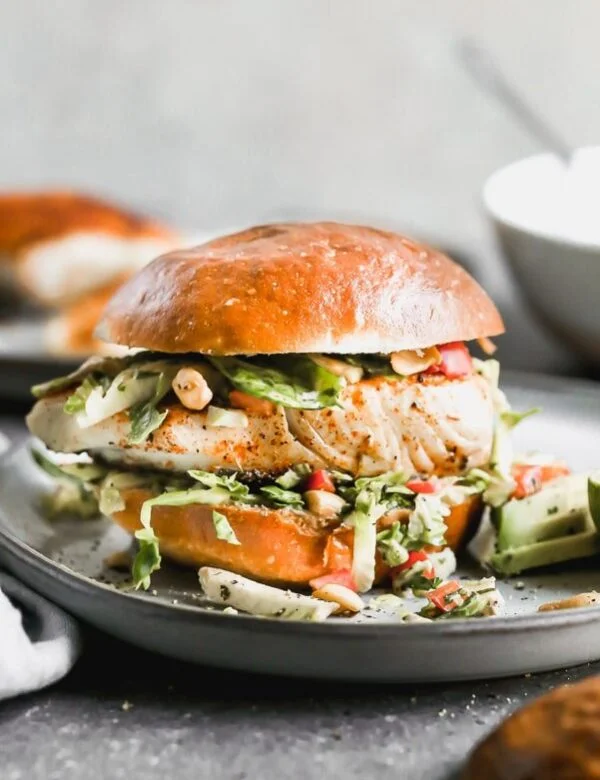 If you want a little taste of vacation,  try out our Blackened Fish Sandwich Recipe. This easy fish sandwich is pan-seared until crusty and blackened on the top and flaky inside, nestled into a brioche bun, and topped with a lime and cumin Brussels sprout slaw. 