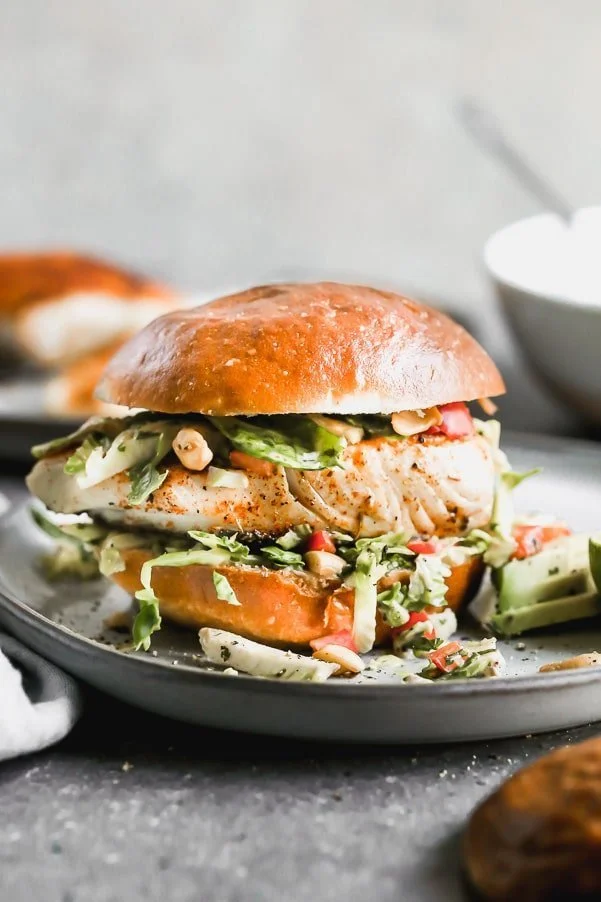 If you want a little taste of vacation,  try out our Blackened Fish Sandwich Recipe. This easy fish sandwich is pan-seared until crusty and blackened on the top and flaky inside, nestled into a brioche bun, and topped with a lime and cumin Brussels sprout slaw. 