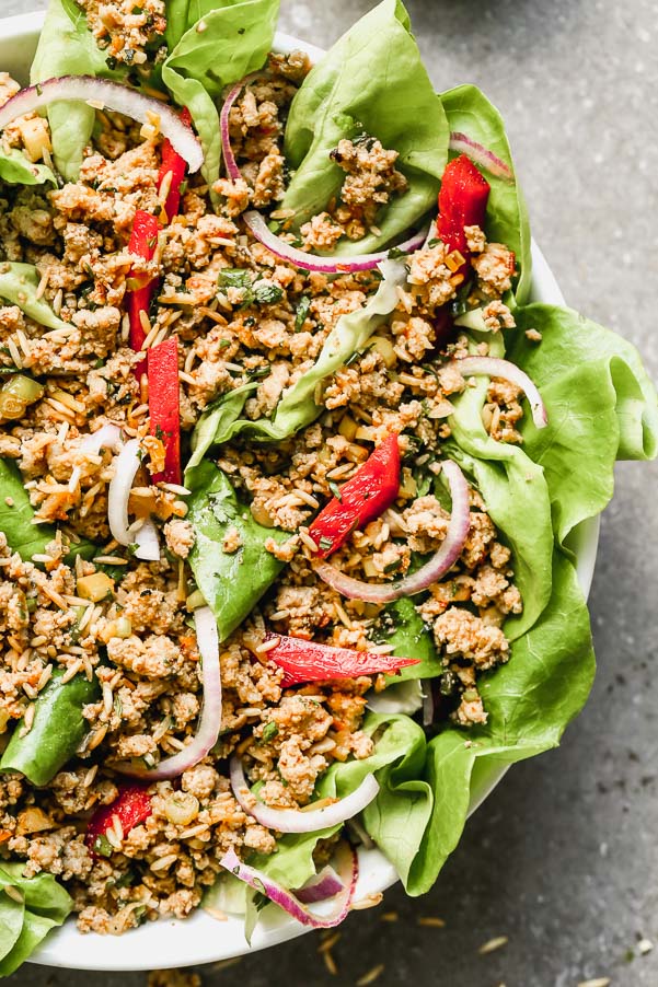 This Easy Chicken Larb Salad is the most FLAVORFUL meal. Ground turkey or chicken is tossed with zesty lime juice, fish sauce, and spicy chili sauce, served over a bed of mixed greens, red bell peppers, and red onion, and topped off with crispy toasted rice. Hearty, healthy, and so delicious.