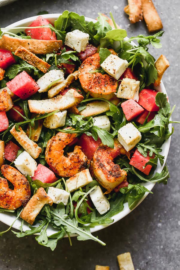 Blackened Shrimp and Halloumi Salad - have you seen a prettier combination? We take take peppery arugula leaves and toss them in a simple vinaigrette and then layer them with sweet watermelon, salty halloumi cheese, toasted pita croutons, and spicy blackened shrimp. It's hearty, healthy, and SO delicious.&nbsp;