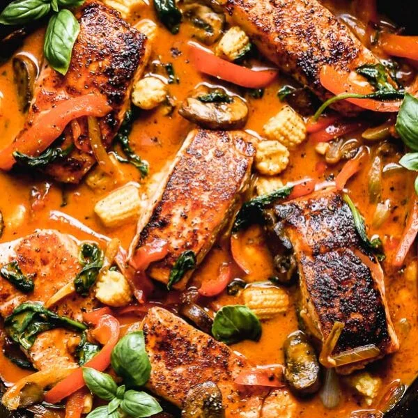 Red Curry Salmon with Veggie is not only a show-stopper to look at, but it's seriously delicious - and easy to make! Yep, this one-pan, 30-minute meal is E-A-S-Y to throw together on a whim, and we can't get enough it. We take center-cut portions of Atlantic salmon, sear them until irresistibly crispy on the outside and buttery on the inside and then simmer them in a sweet and spicy coconut curry sauce. We nestle in tons of veggies - portabella mushrooms, baby corn, spinach, red peppers, and onions - and then sprinkle it with a little bit of fresh basil. SO good. 