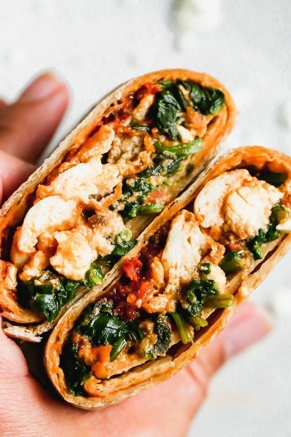 Our Copycat Starbucks Spinach Feta Wrap is the perfect on-the-go breakfast for busy mornings. We stuff a whole-wheat tortilla with egg whites, wilted baby spinach, salty feta, and a sun-dried tomato pesto. The wraps are crisped up in a hot skillet until golden brown and ready to eat. 