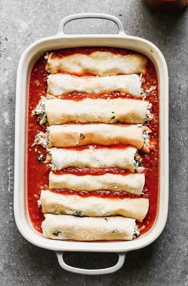 Chicken cannelloni lined up in a baking dish