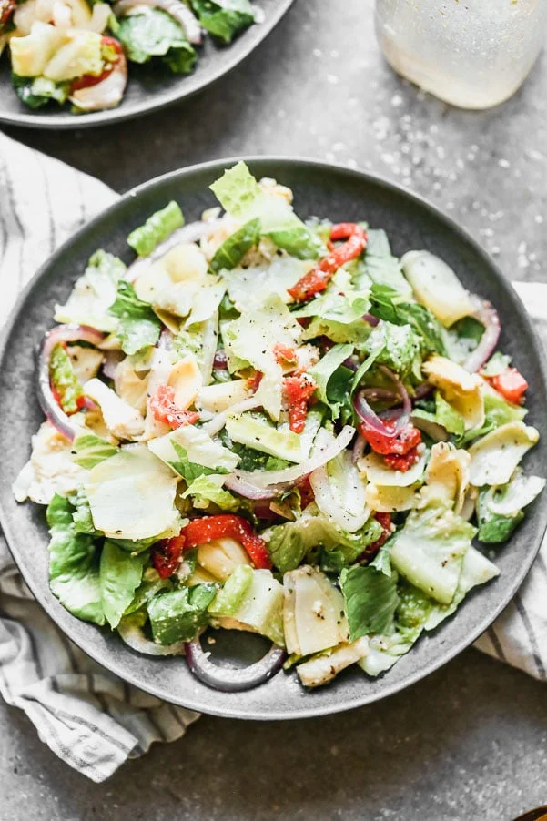 Italian Artichoke Salad is our go-to salad for cozy winter dinners, alfresco summer barbecues and everything in between. We marinate artichoke hearts and red onions in a zippy red wine and parmesan vinaigrette, toss everything with crisp romaine lettuce and sliced roasted red peppers. Easy to make ahead of time, perfect to feed a large family, and delicious.&nbsp;