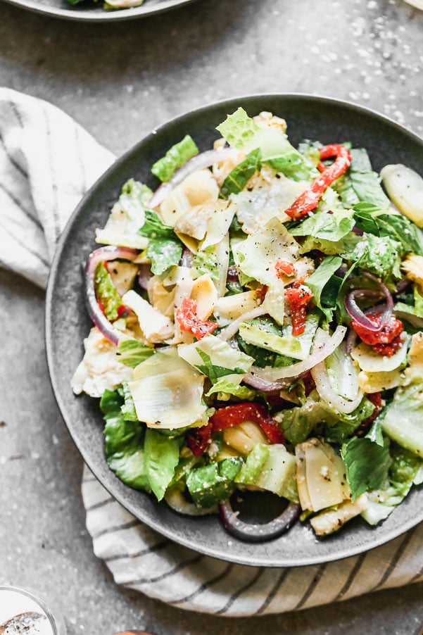 Italian Artichoke Salad is our go-to salad for cozy winter dinners, alfresco summer barbecues and everything in between. We marinate artichoke hearts and red onions in a zippy red wine and parmesan vinaigrette, toss everything with crisp romaine lettuce and sliced roasted red peppers. Easy to make ahead of time, perfect to feed a large family, and delicious.&nbsp;