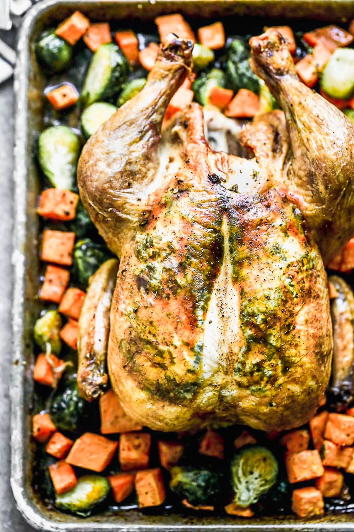 Our Crispy Roast Chicken is a cozy meal that's going to carry us through spring. We take a simple crispy roast chicken recipe and elevate it just a touch with an easy sage butter nestled under the skin, and a brown butter and sweet pomegranate juice glaze on top of the skin. We surround the chicken with hearty Brussels sprouts and sweet potatoes to make this easy meal come full circle.