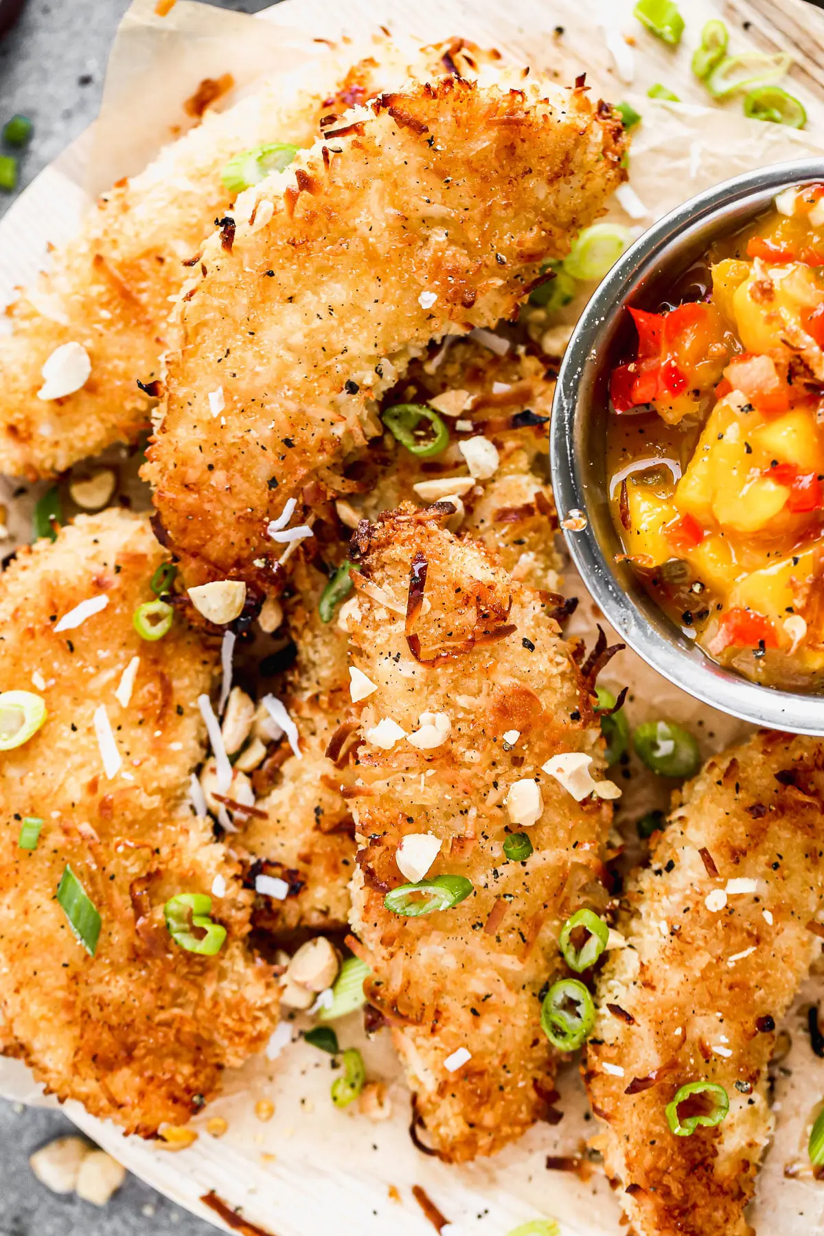 Let's all satisfy the kid in us with these ultra crispy, completely irresistible Baked Coconut Chicken Tenders. We coat tender chicken in a light coconut and panko breading, bake them on a screaming hot baking sheet and then serve them with a quick warm mango salsa and a hot honey drizzle. 