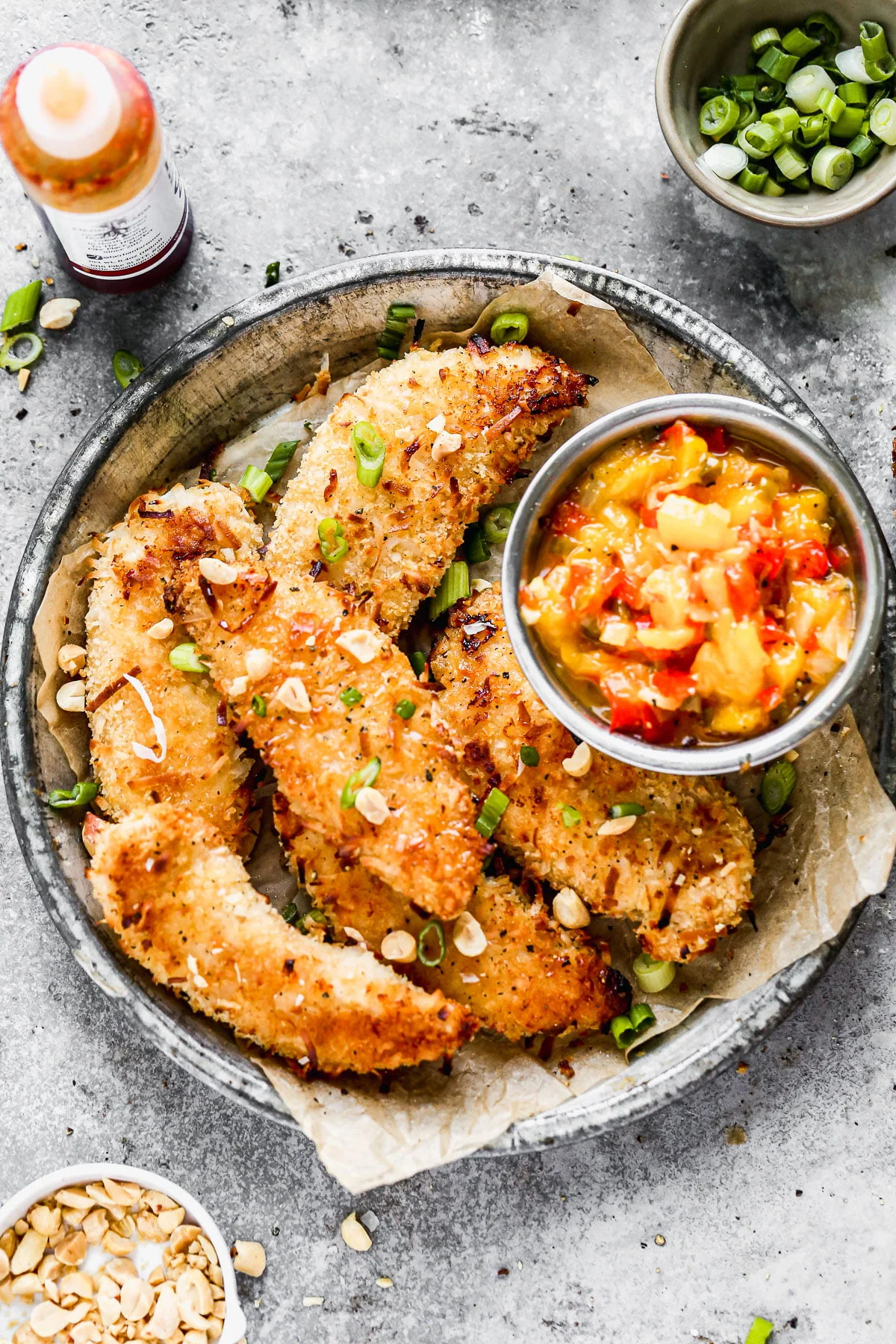 Let's all satisfy the kid in us with these ultra crispy, completely irresistible Baked Coconut Chicken Tenders. We coat tender chicken in a light coconut and panko breading, bake them on a screaming hot baking sheet and then serve them with a quick warm mango salsa and a hot honey drizzle.&nbsp;
