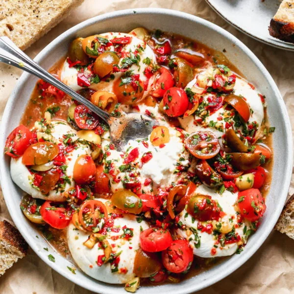 This Calabrian Chili and Burrata Appetizer is going to be the star of all your summer gatherings. This is basically a classic bruschetta but so so much better. We take juicy heirloom cherry tomatoes and toss them with fiery calabrian chilis, zippy red wine vinegar, parsley, garlic, and a few briny capers. We spoon it over the most adorable mini creamy burrata balls and serve with crusty bread to soak up every juicy bite. 