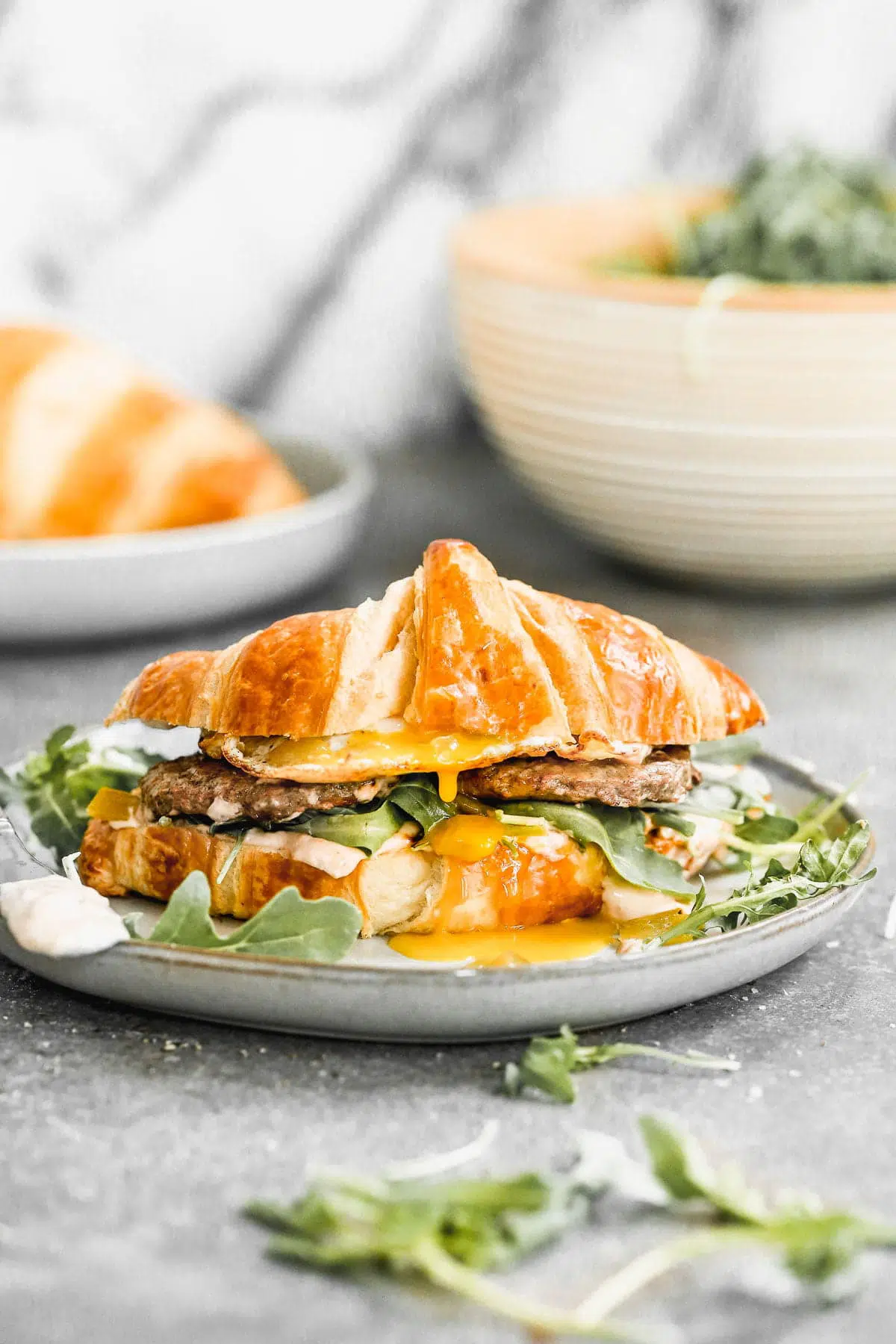 Calling all breakfast lovers! Our Croissant Breakfast Sandwich is slathered with a spicy salsa cream cheese, topped with smoky green chiles, peppery arugula, salty Turkey Sausage, and of course, a drippy over-easy egg. Hearty, messy, and oh-so delicious.