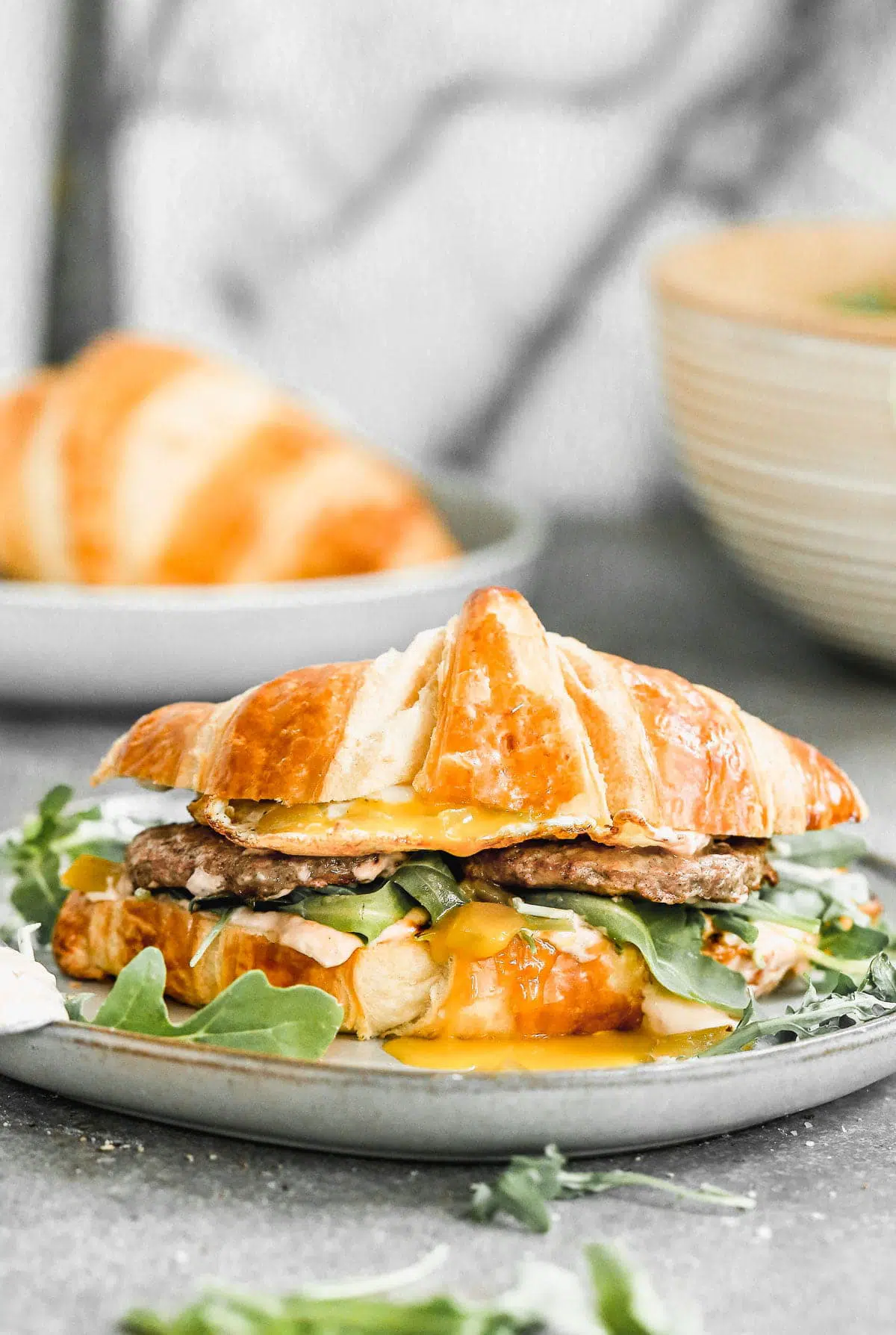 Calling all breakfast lovers! Our Croissant Breakfast Sandwich is slathered with a spicy salsa cream cheese, topped with smoky green chiles, peppery arugula, salty Turkey Sausage, and of course, a drippy over-easy egg. Hearty, messy, and oh-so delicious.