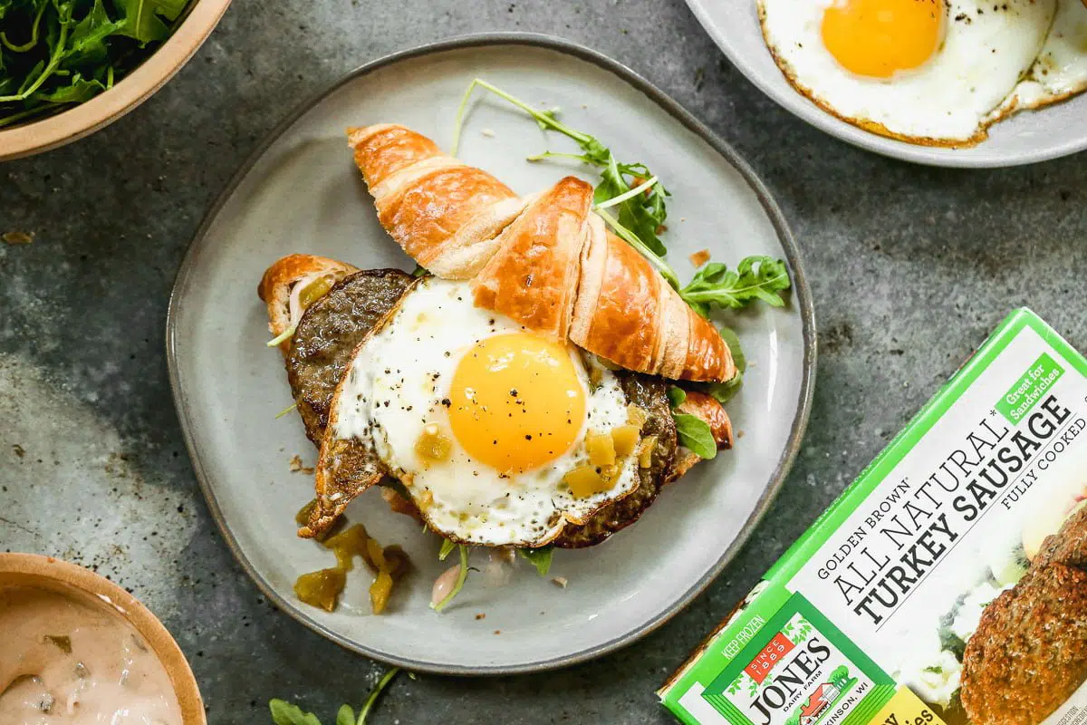 Calling all breakfast lovers! Our Croissant Breakfast Sandwich is slathered with a spicy salsa cream cheese, topped with smoky green chiles, peppery arugula, salty Turkey Sausage, and of course, a drippy over-easy egg. Hearty, messy, and oh-so delicious.
