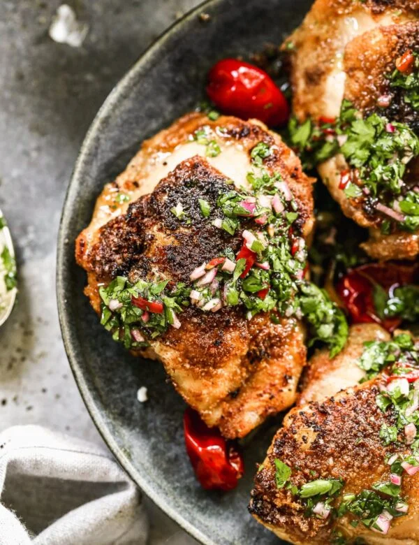 Air Fryer Chicken Thighs are a true winner in the realm of delicious, easy chicken dinners. We dust bone-in, skin-on chicken thighs with garlic, onion, and cumin then cook them inn the air fryer until the skin is irresistibly crispy and the inside is tender and moist. We drizzle it all with a fiiery chimichurri and dig in!