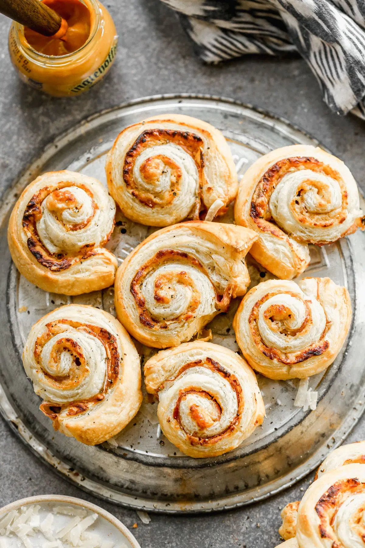 Puff Pastry Pinwheels made with store-bought puff pastry sheets, sweet and hot mustard, nutty parmigiano reggiano and  salty paper-thin slices of prosciutto. Sure to be the hit of your party!